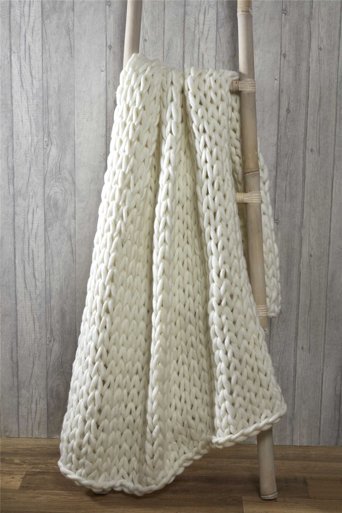 Close-up of a soft, textured cable knit throw showcasing its thick, chunky knit pattern perfect for winter warmth