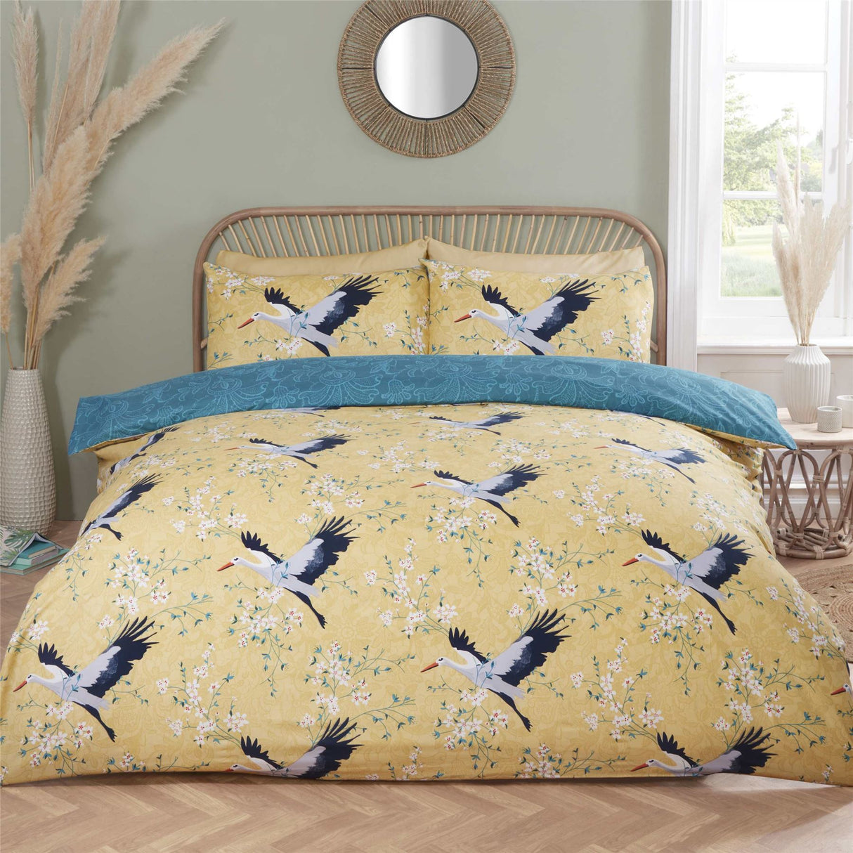 Close-up of the Cranes Duvet Set showcasing the delicate cranes in flight on an ochre backdrop, featuring a reversible lace pattern in teal for versatile styling