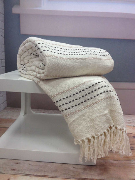 A cosy bed featuring the Stitch Stripe Throw with its colourful striped design and tasselled trim