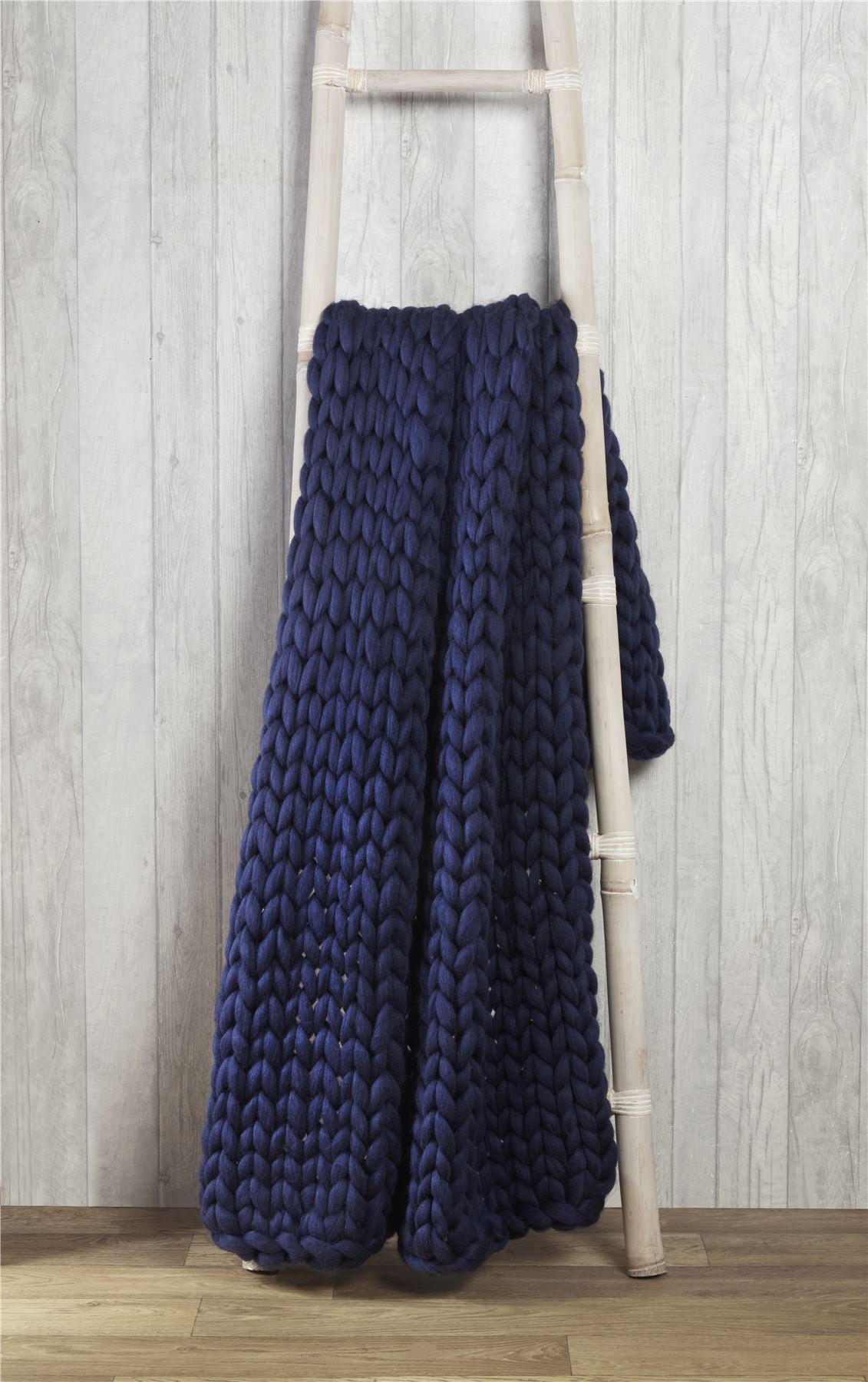 A cosy sofa adorned with a plush cable knit throw, ideal for keeping warm during chilly evenings