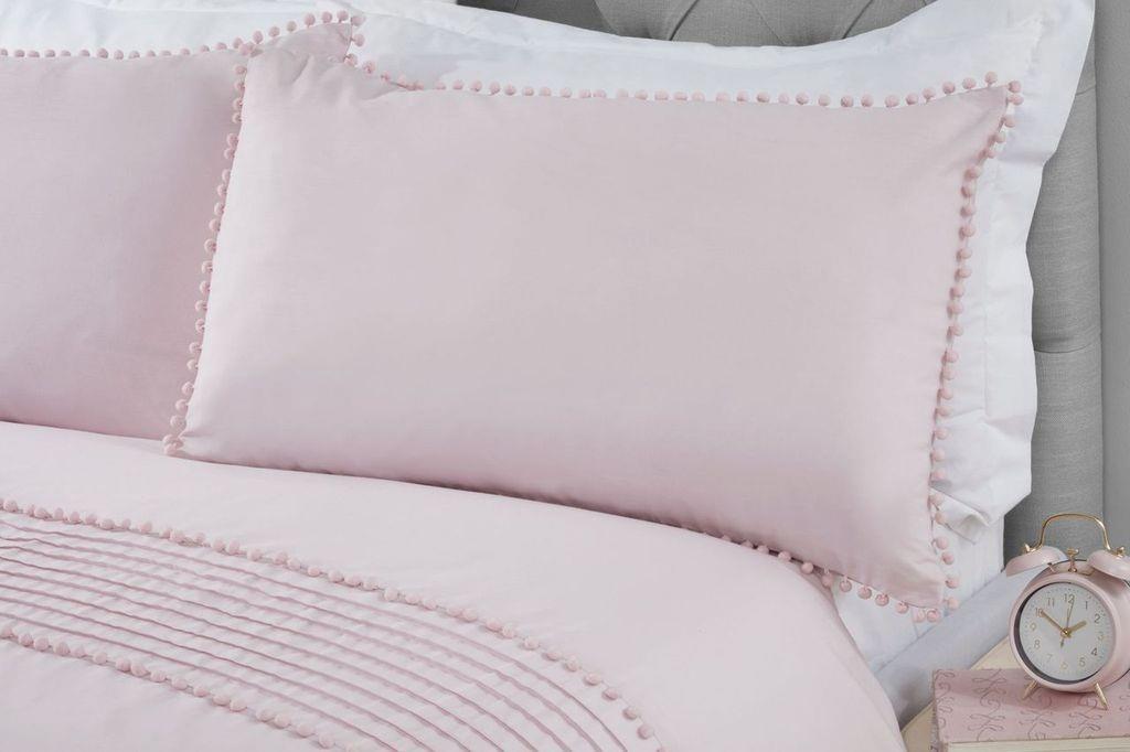 A styled bedroom scene showcasing the Pom Poms Duvet Set with grey bobble trim on the pillowcases and duvet cover