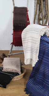 The Stitch Stripe Throw draped over a bed, illustrating its versatile use on beds, chairs, and sofas