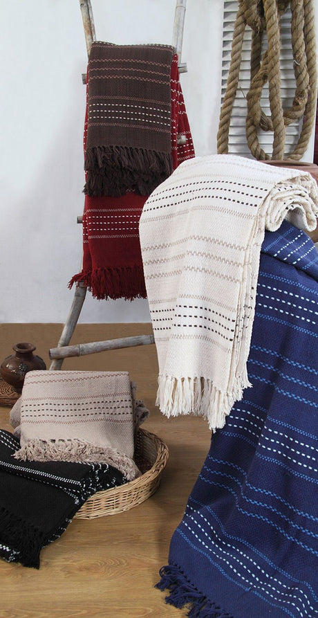The Stitch Stripe Throw draped over a bed, illustrating its versatile use on beds, chairs, and sofas