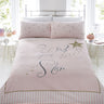 Blush pink duvet set with scrolly writing and gold stars, featuring stripe print border and star speckled pillowcases in single, double, or kingsize Made from easycare fabric with panel printed pillowcases and popper closing mechanism