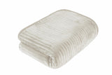 The plush ribbed mink blanket casually draped over a modern chaise lounge for a cosy look