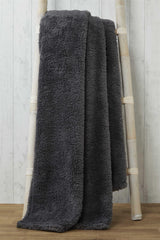 Elegant teddy throw folded neatly on a bedroom bed, showcasing its thick, inviting material