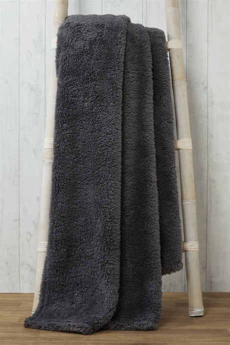 Elegant teddy throw folded neatly on a bedroom bed, showcasing its thick, inviting material