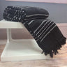 Warm cotton Stitch Stripe Throw with striped woven pattern and tasselled edges draped over a sofa