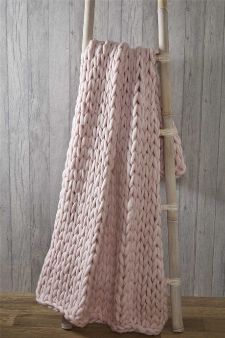Luxurious cable knit chunky throw draped over a cosy armchair in a stylish living room