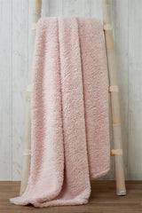 Luxurious plush teddy throw draped over a cosy armchair in a warmly lit living room