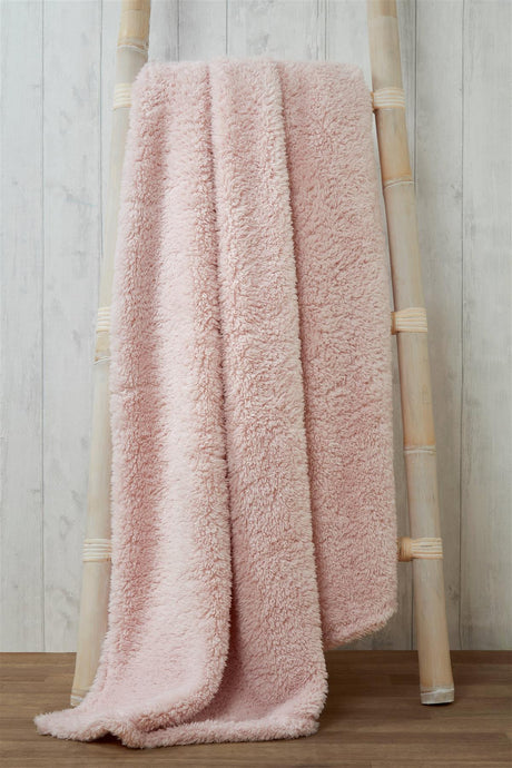 Luxurious plush teddy throw draped over a cosy armchair in a warmly lit living room