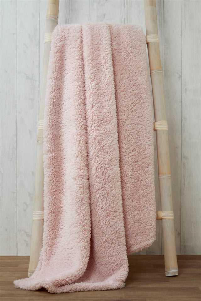 Luxurious plush teddy throw draped over a cosy armchair in a warmly lit living room