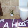 Luxurious natural cotton bath mat featuring the word bath in elegant lettering alongside a matching pedestal mat