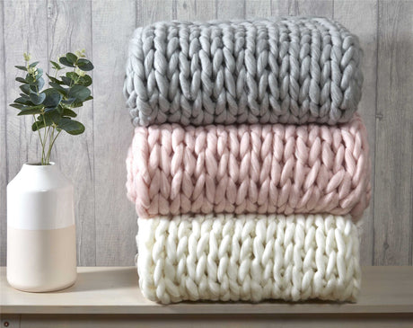 Brightly lit lounge area with a cable knit chunky throw tossed casually over a sofa, enhancing room sophistication