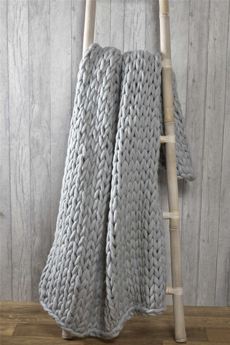 Elegant bedroom setting featuring a cable knit throw folded neatly at the foot of the bed, adding style and comfort