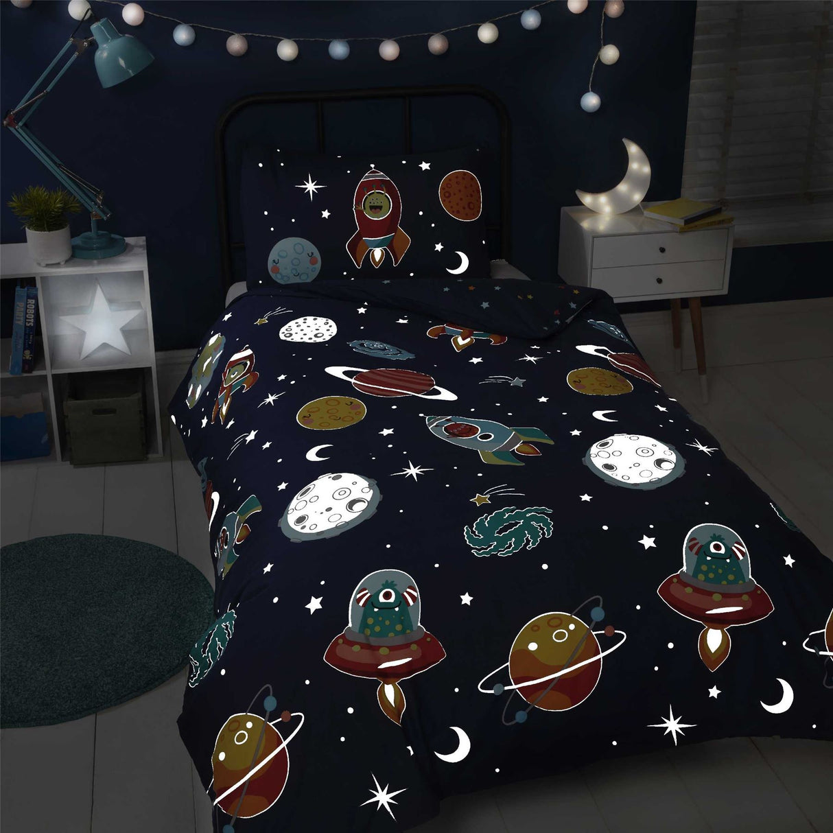 A fun space themed bedding set with images of planets, stars, aliens, and a spaceship on a dark blue background that glows in the dark for kids' bedrooms
