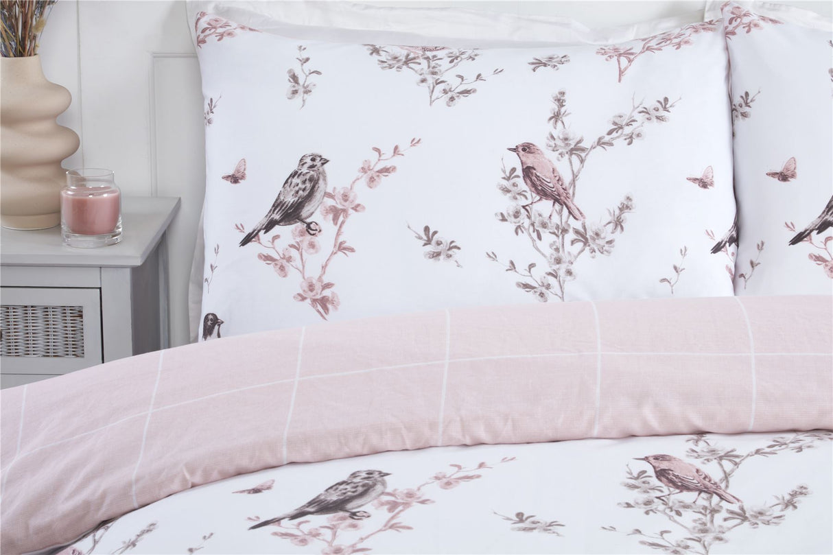 A soft, reversible bedding collection in pink showcasing a vintage toile design with popper closures and matching pillowcases