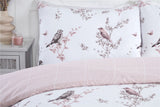 A soft, reversible bedding collection in pink showcasing a vintage toile design with popper closures and matching pillowcases