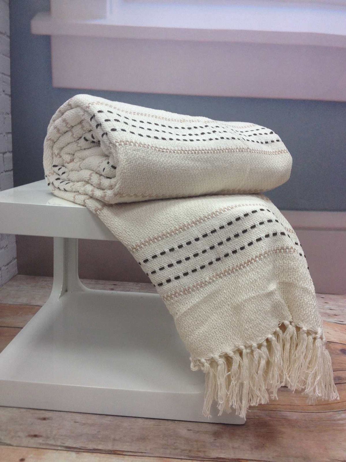 A cosy bed featuring the Stitch Stripe Throw with its colourful striped design and tasselled trim