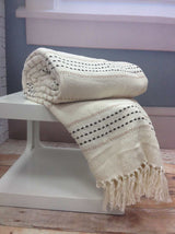 A cosy bed featuring the Stitch Stripe Throw with its colourful striped design and tasselled trim