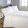 Close-up of waffle-textured bedding with contrasting plain top border and decorative buttons