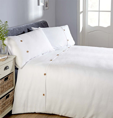Close-up of waffle-textured bedding with contrasting plain top border and decorative buttons