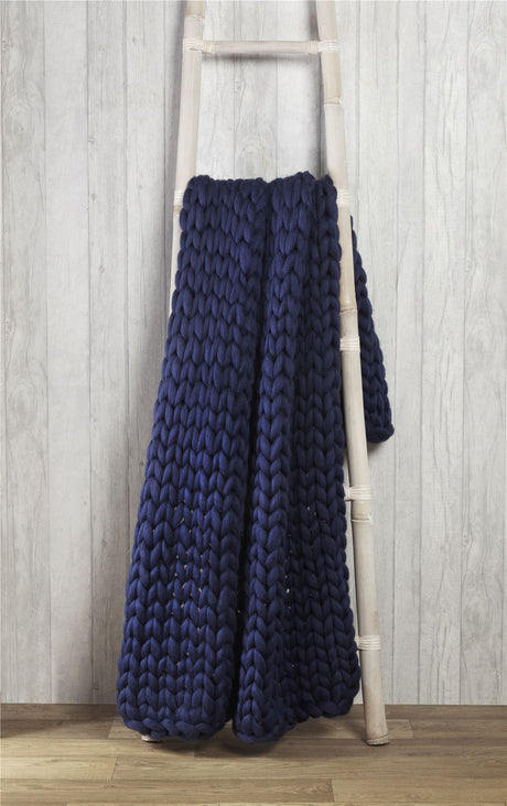 A cosy sofa adorned with a plush cable knit throw, ideal for keeping warm during chilly evenings