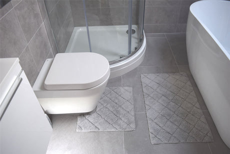 Luxury bathroom accessory set including a large bath mat with diamond pattern and a compact pedestal mat